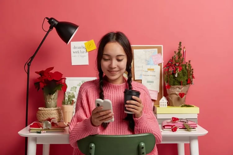 une femme chez elle sourit en étant sur son téléphone
